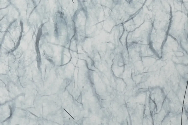 Close-up of a handmade paper with many reddark and textile fibers in it