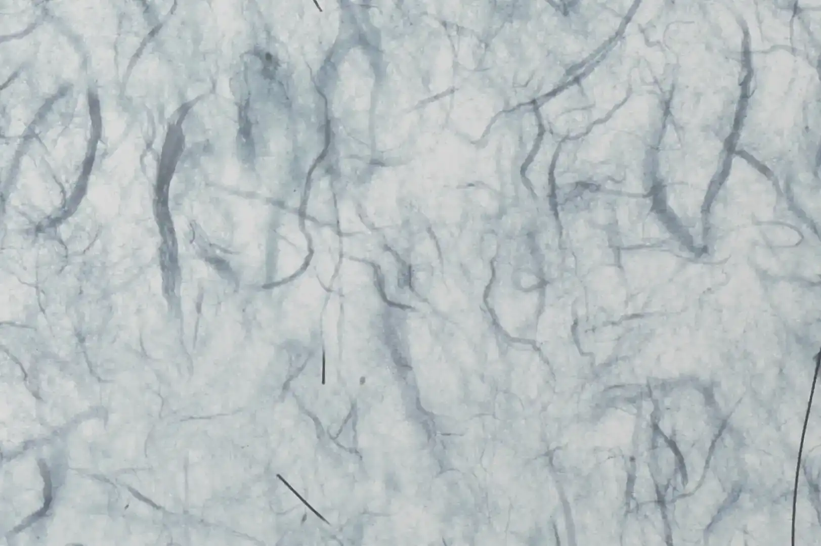 Close-up of a handmade paper with many reddark and textile fibers in it