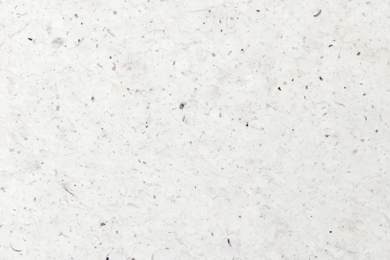 Close-up of an uneven handmade white paper with lots of threads and specks
