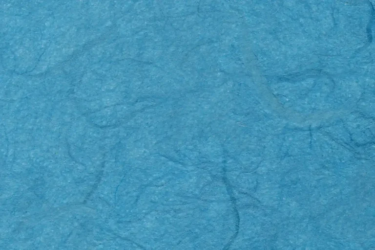 Close-up of a handmade blue paper with random darker fibers