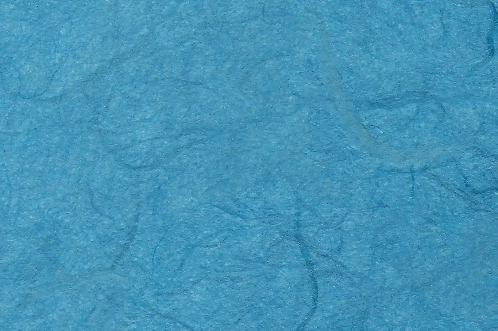 Close-up of a handmade blue paper with random darker fibers