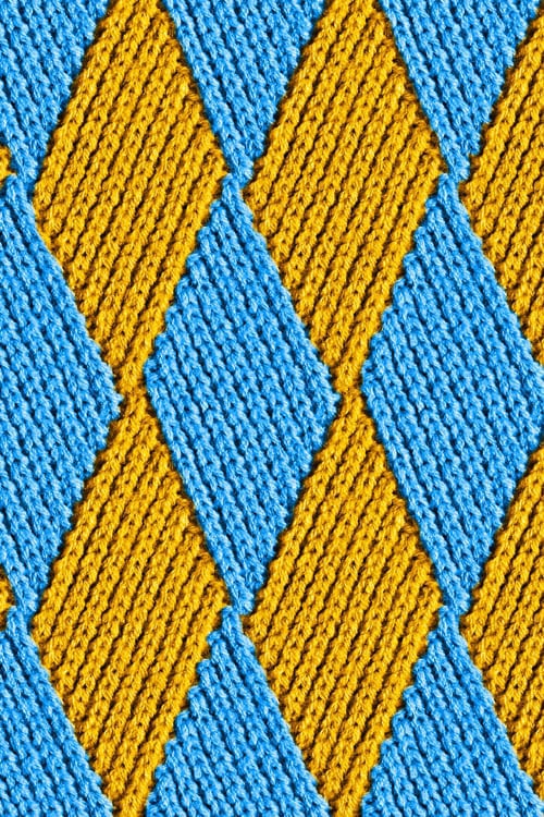 Close-up of a knitted diamond pattern pullover with yellow and blue yarns
