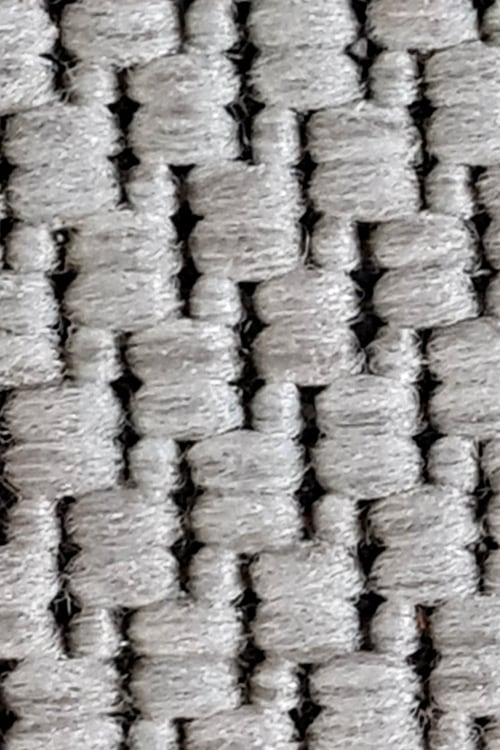Close-up of a rough carpet with chunky black but mostly white fibers