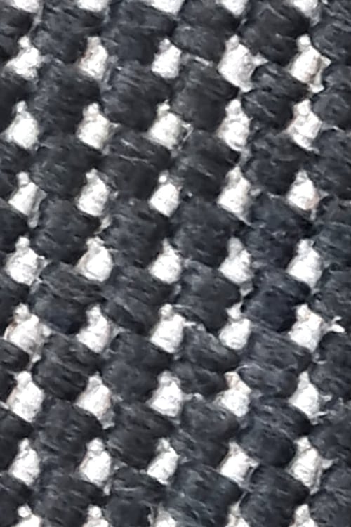 Close-up of a rough carpet with chunky black and white fibers