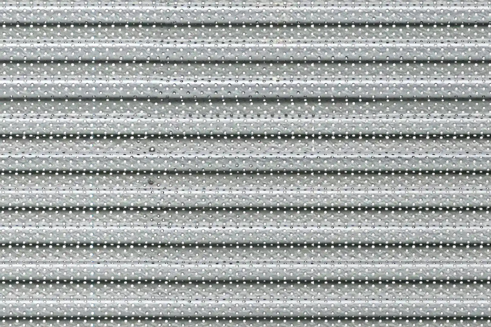 Close-up of a smooth undulating perforated metal sliding shopfront