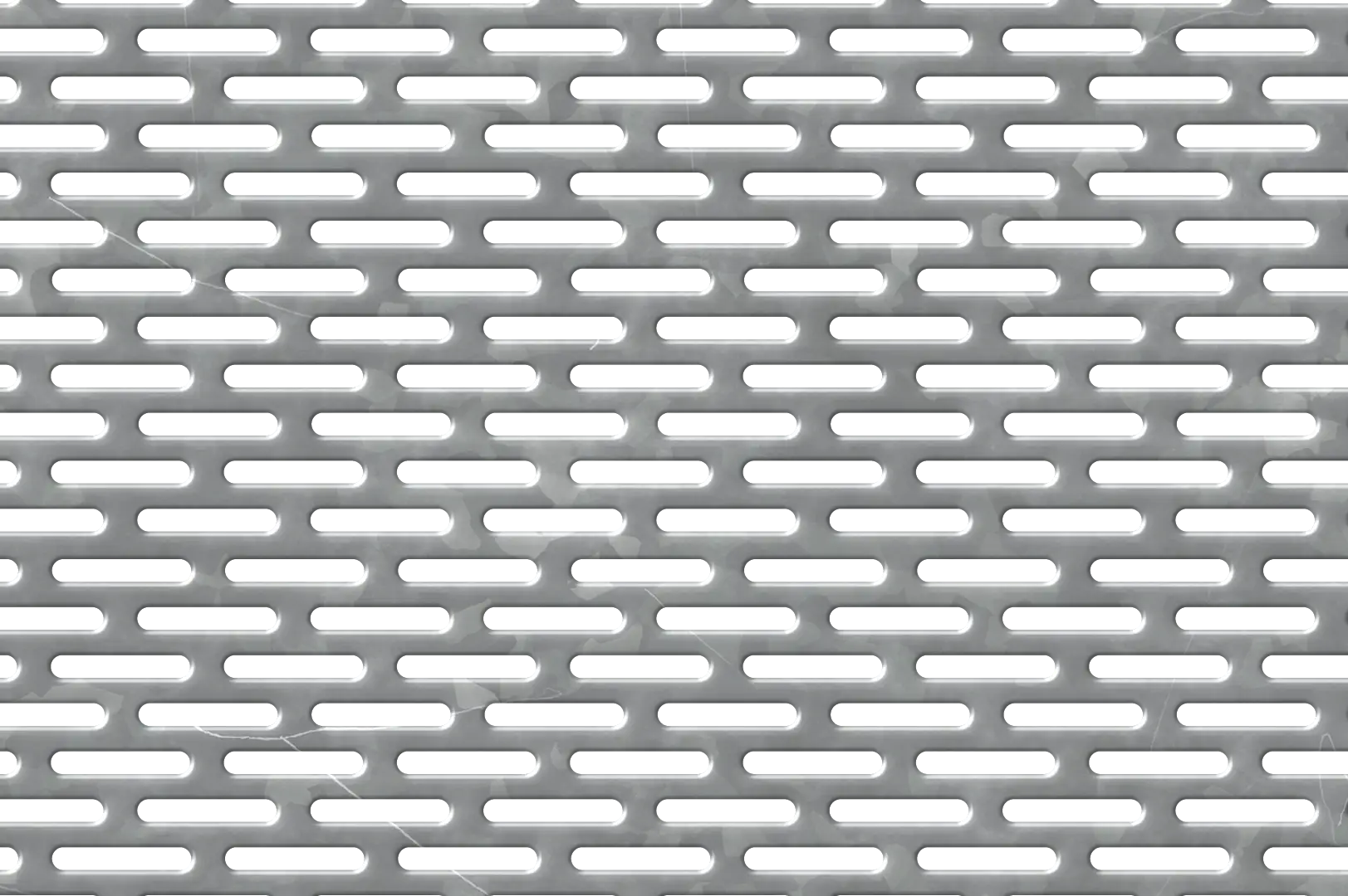 Close-up of a perforated galvanized metal sheet with elongated pill shaped holes