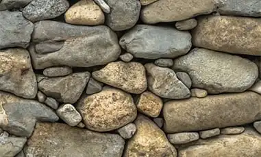 Stone wall with different sized round stones stacked on each other