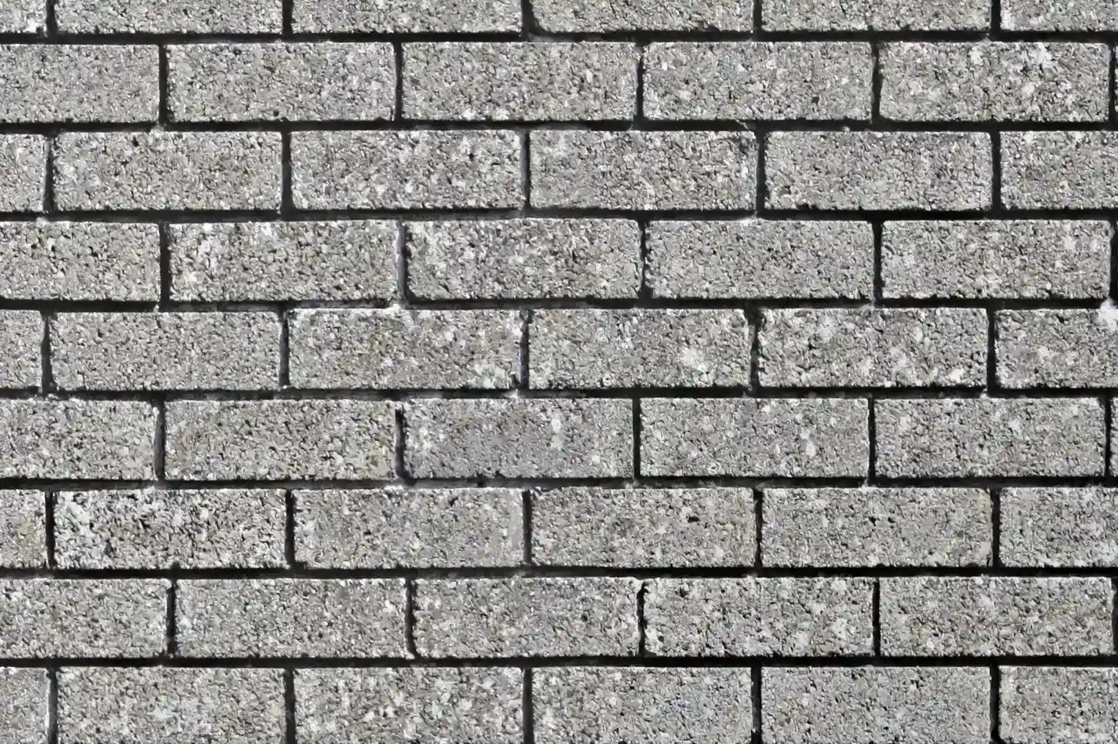 Close-up of a grey, aged brick wall with recessed joints