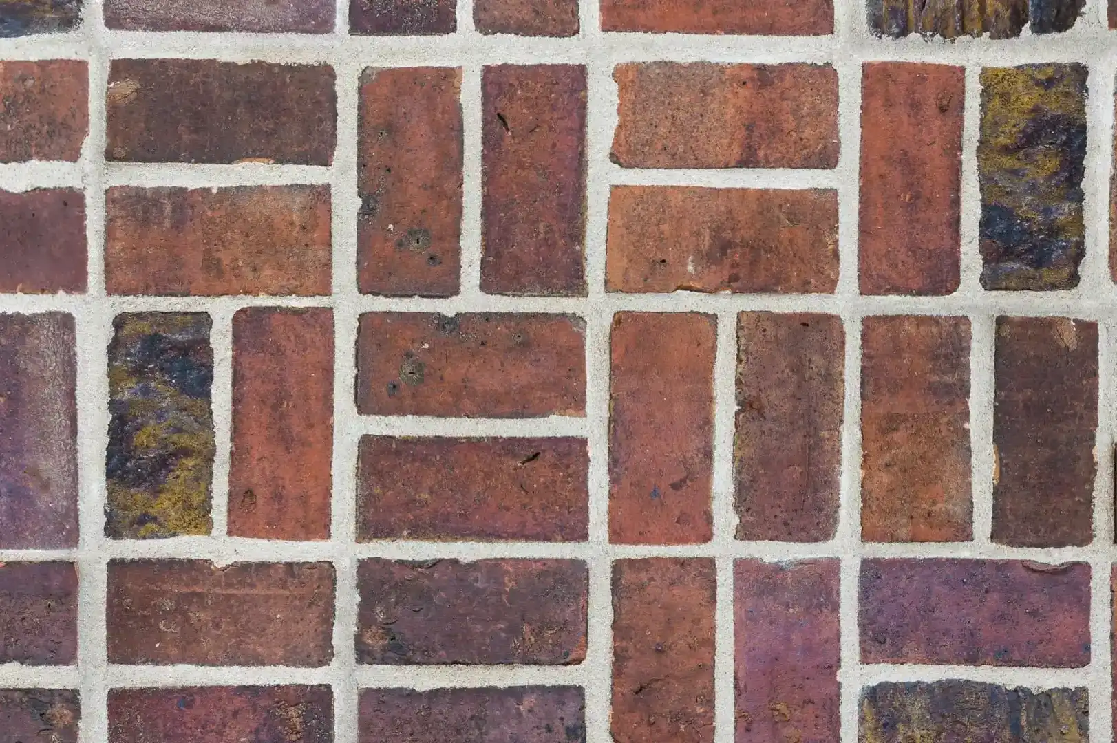 Close-up of a decorative brick wall with dark brown and purplish bricks and white mortar