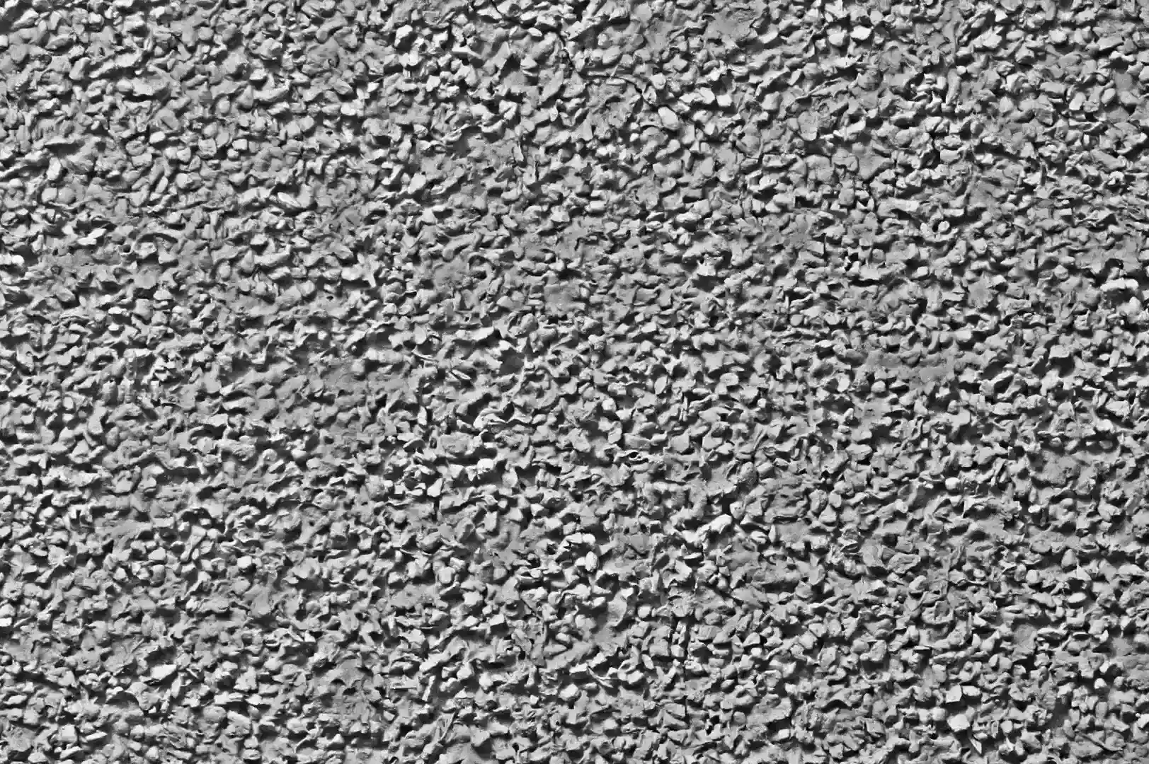 Close-up of a grey plaster wall with pebbles
