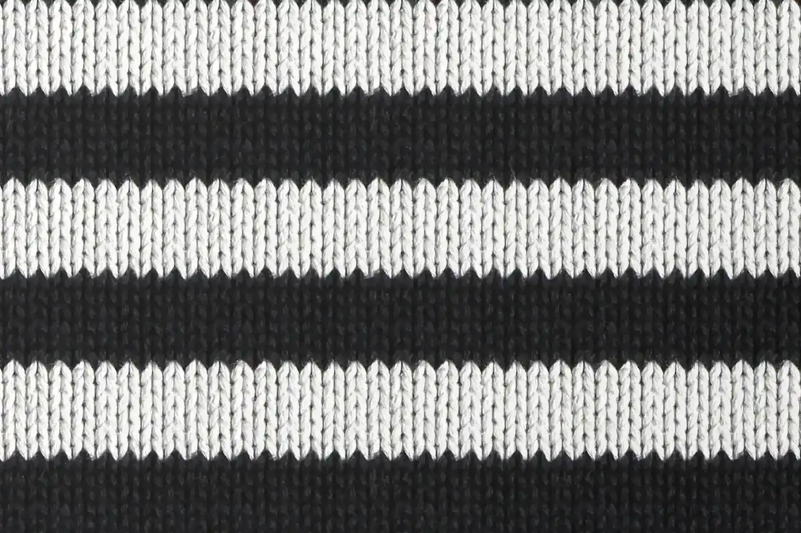 Close-up of a knitted polyester pullover with black and white horizontal stripes