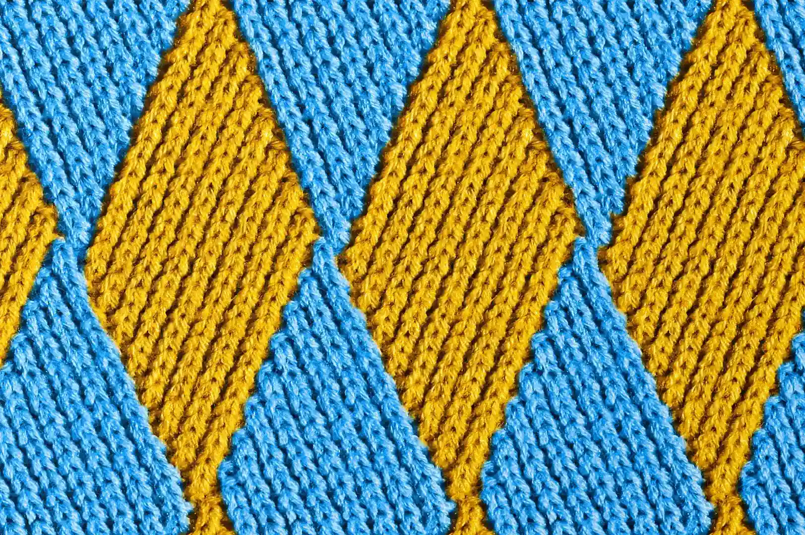 Close-up of a knitted diamond pattern pullover with yellow and blue yarns