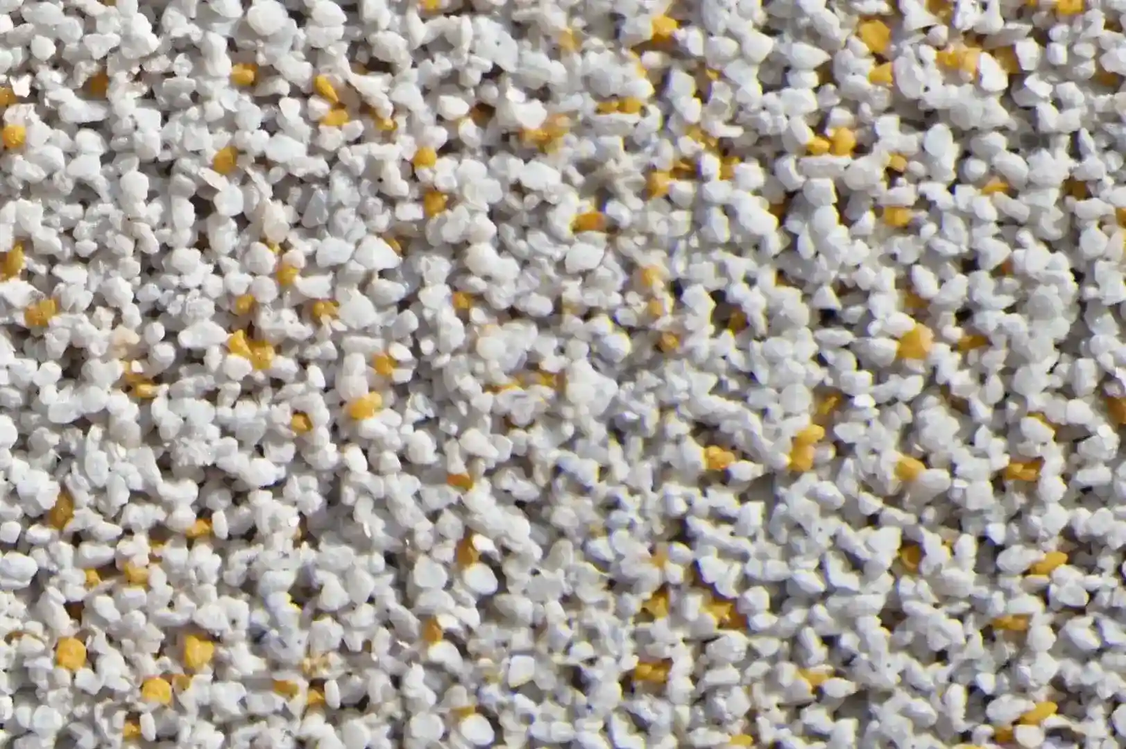 Close-up of a decorative grainy cement wall with fine white and yellow aggregate