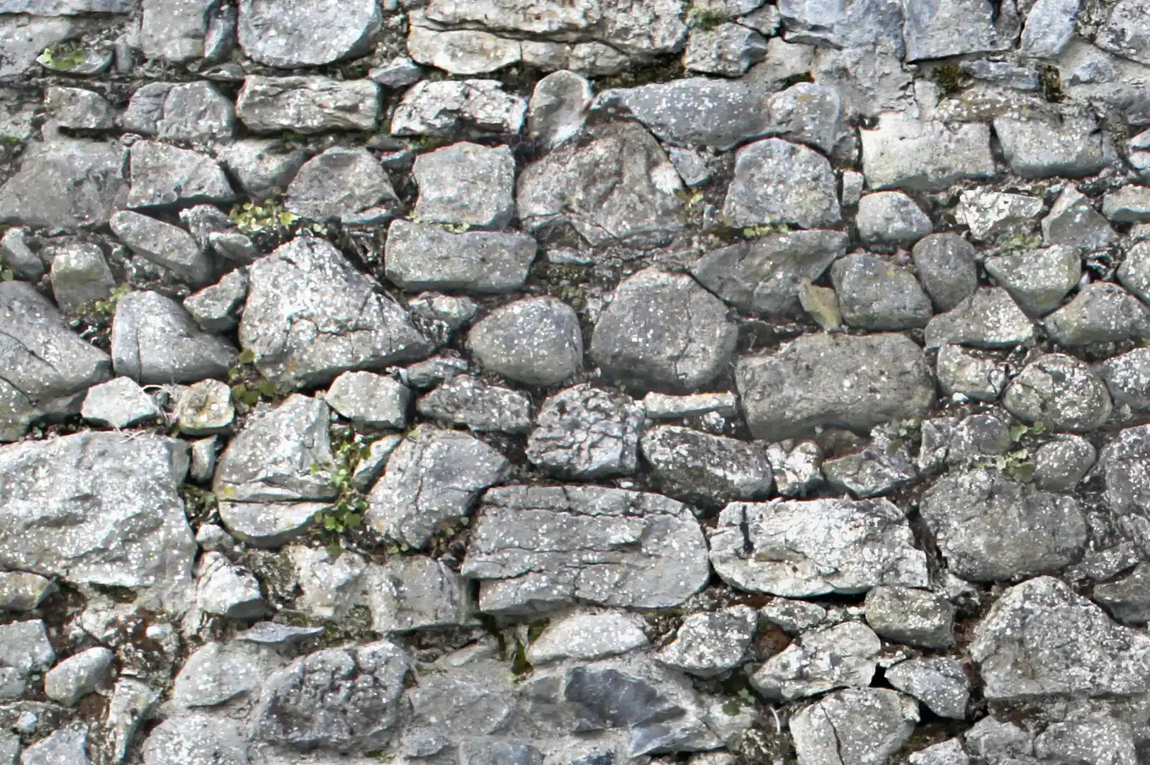 Close-up of an irregular old stone wall with moss on it