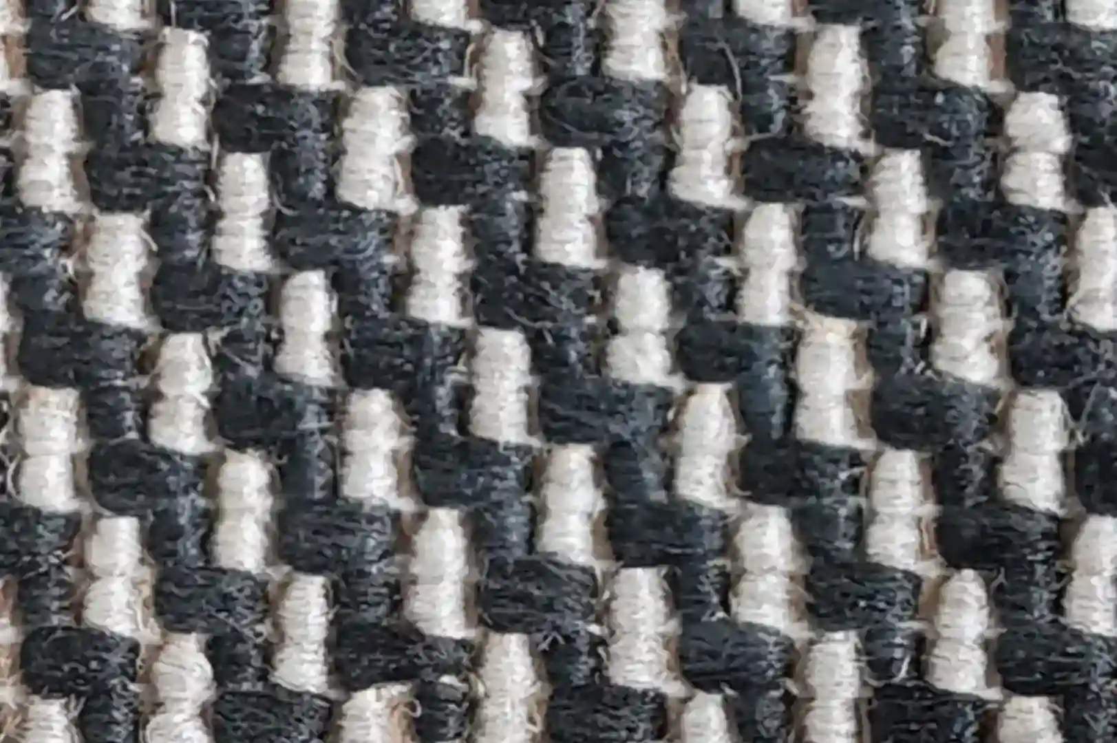 Close-up of a rough carpet with black and white fibers arranged in a zigzag pattern