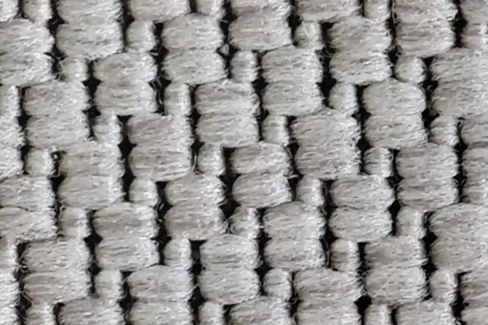 Close-up of a rough carpet with chunky black but mostly white fibers