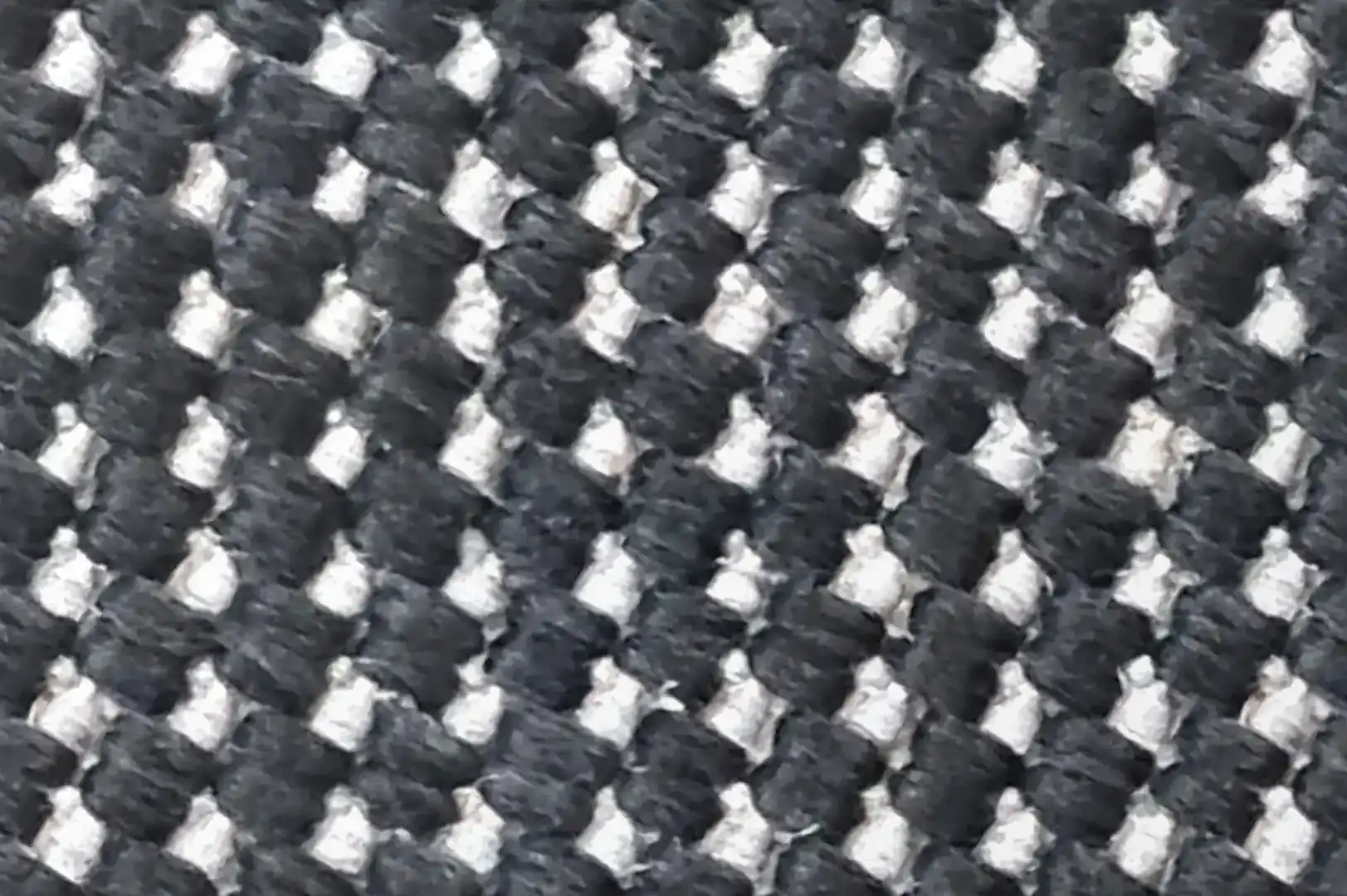 Close-up of a rough carpet with chunky black and white fibers